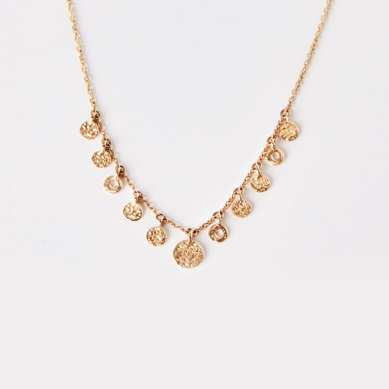 The abacus disk diamond necklace by bluboho, crafted in 14k yellow gold, features a delicate chain adorned with multiple small, textured circular pendants of varying sizes. These pendants are evenly spaced along the lower half of the chain, creating an elegant and minimalistic design against a plain white background.