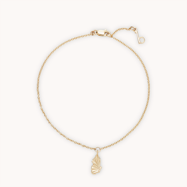 The metamorphosis butterfly wing bracelet by bluboho is an elegant and minimalist 14k yellow gold piece, featuring a fine chain and a small butterfly charm. The bracelet has a lobster claw clasp for secure fastening and an additional short chain with a loop to allow for adjustable sizing.