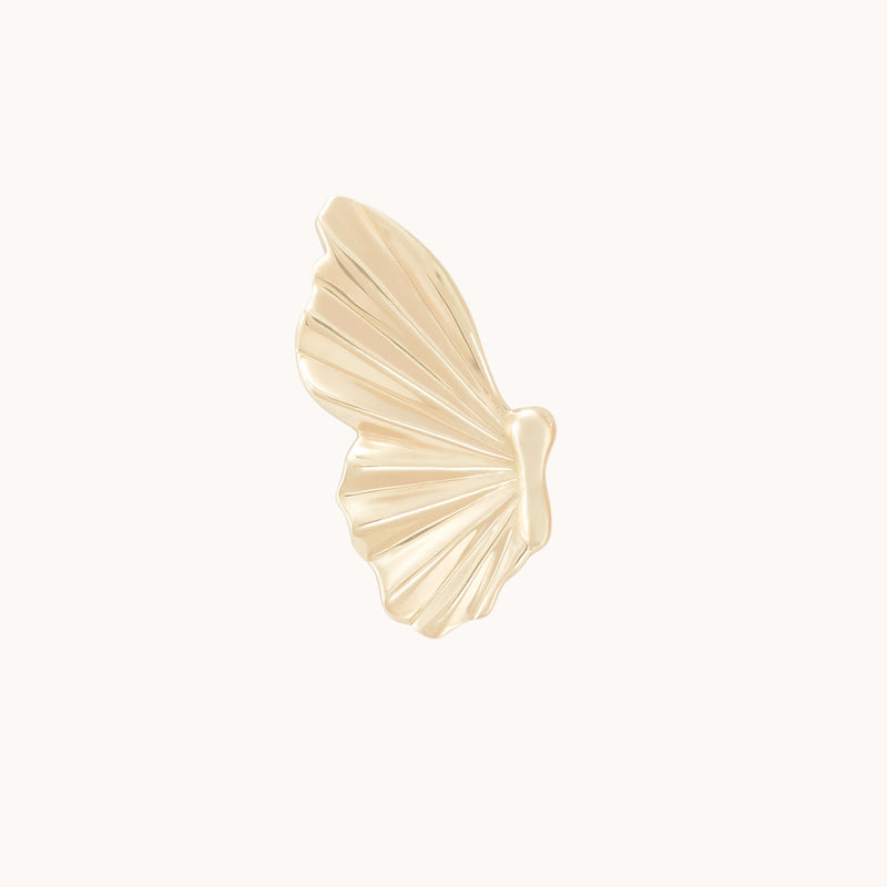 The "metamorphosis butterfly wing earring" in 14k yellow gold by bluboho resembles a delicate butterfly wing. It features subtle grooves and edges, giving it a textured, slightly ribbed appearance against a plain white background, emphasizing its elegant design.