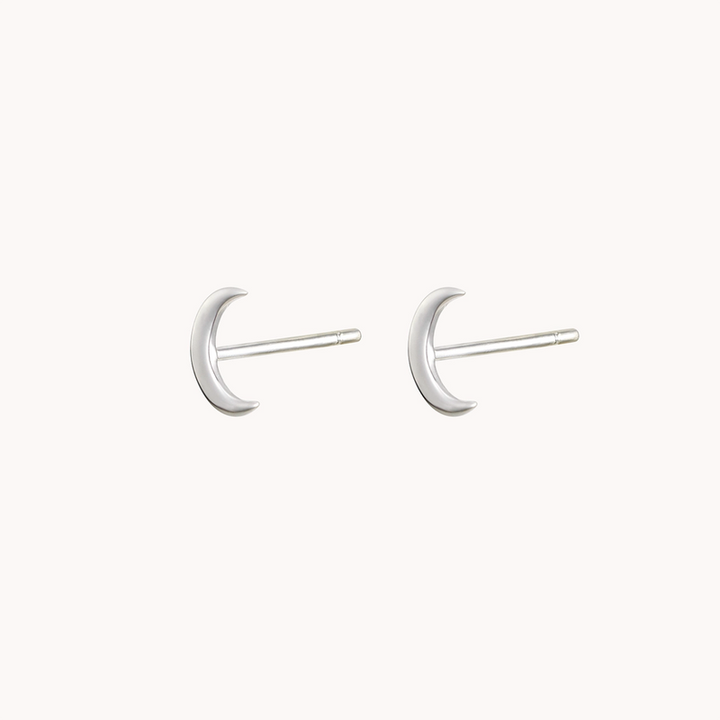 Image of a pair of Bluboho's Crescent Moon Earring Silver - Sterling Silver. The minimalist stud earrings have a smooth surface and are designed for pierced ears. They are set against a plain white background, highlighting their simplicity and elegance.