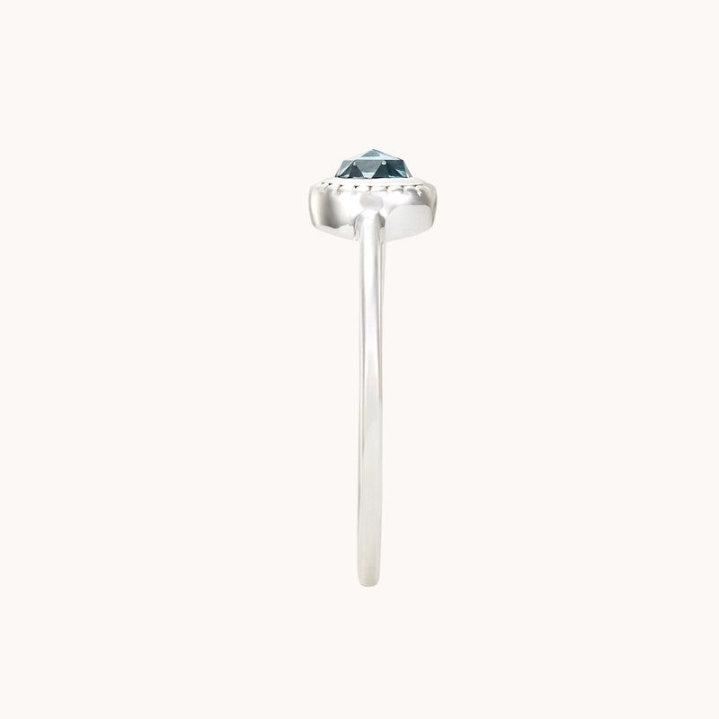 A slender sterling silver ring, the full moon london blue topaz ring by bluboho, showcasing a single blue gemstone held in a six-prong setting, viewed from the side against a white background.