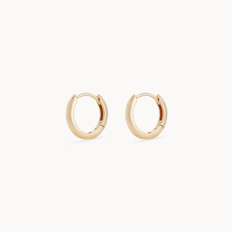 A pair of bluboho dagger small hoop earrings in 14k yellow gold displayed against a plain white background. The design is minimalistic and modern, with a smooth and polished finish.