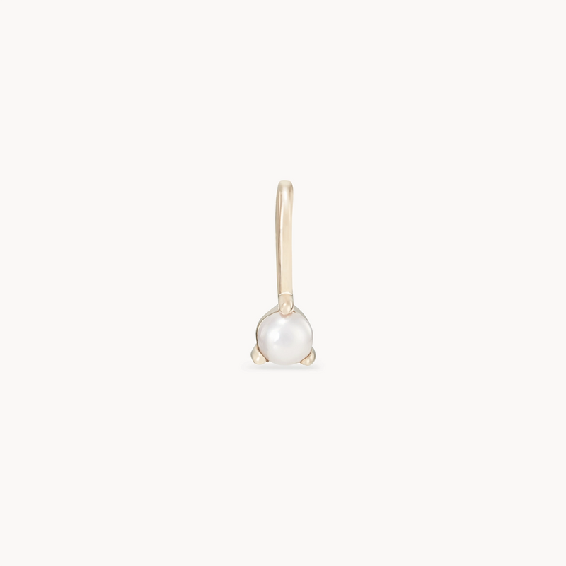 Introducing the serendipity june birthstone charm by bluboho. Crafted in 10k yellow gold, this single earring boasts a simple hook design. Adorned with a small, round white pearl set in a minimalistic gold clasp, it exudes an elegant and delicate look against its plain white background.