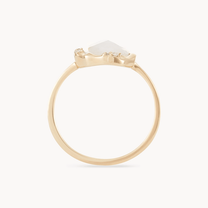 A close-up view of the "moonstone mood ring - 14k yellow gold" by bluboho, featuring a hexagonal, translucent white gemstone set in a minimalist prong setting. The ring's elegant and simple design showcases its delicate craftsmanship against a plain white background.