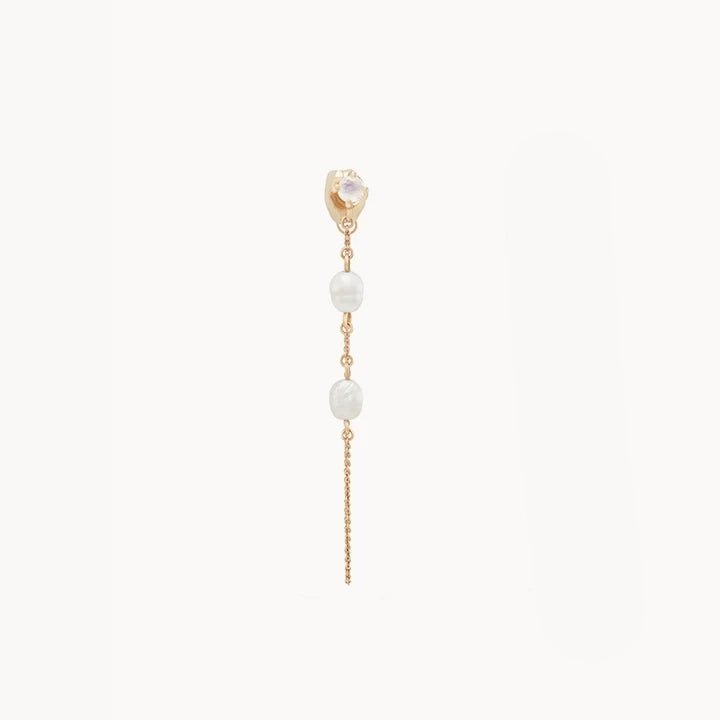 The luna perla pearl chain earring by bluboho is displayed against a white background. This 14k yellow gold earring showcases a small, round crystal-like stud at the top, followed by two small white pearls interspersed with gold links, and a delicate gold chain hanging down from the bottom.