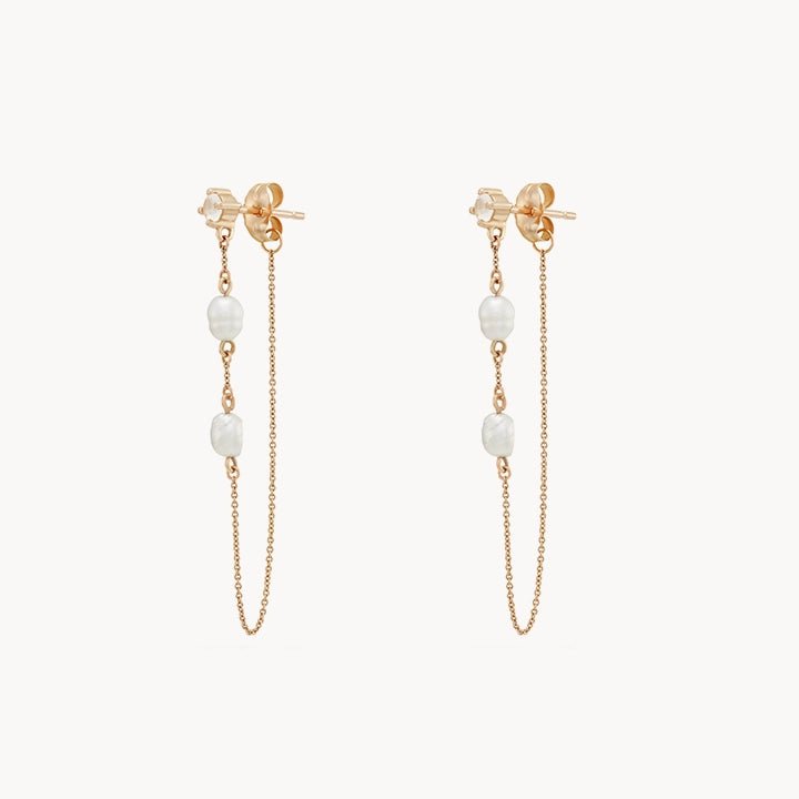 Introducing the luna perla pearl chain earring by bluboho - crafted in 14k yellow gold, these exquisite earrings feature three evenly spaced freshwater pearls connected by thin, delicate gold chains. Designed with push-back closures and a minimalist, elegant appeal, they are perfect for both casual and formal occasions.