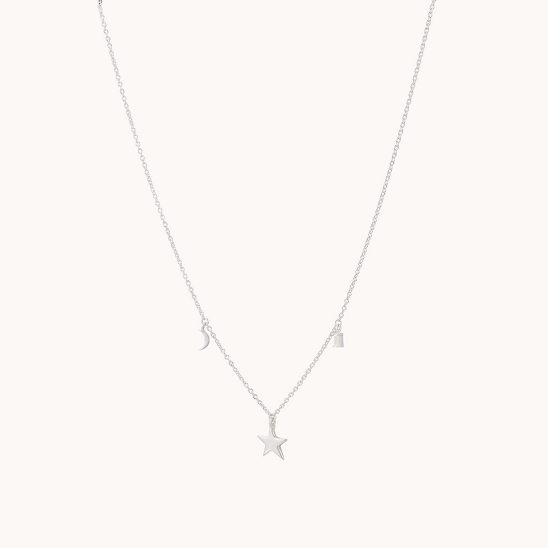 Introducing the Bright Star White Topaz Baguette Necklace by bluboho: a delicate sterling silver piece featuring three small charms. On the left, a crescent moon, in the center, a star, and on the right, a rectangular tag all hang gracefully from a fine chain against a plain white background.