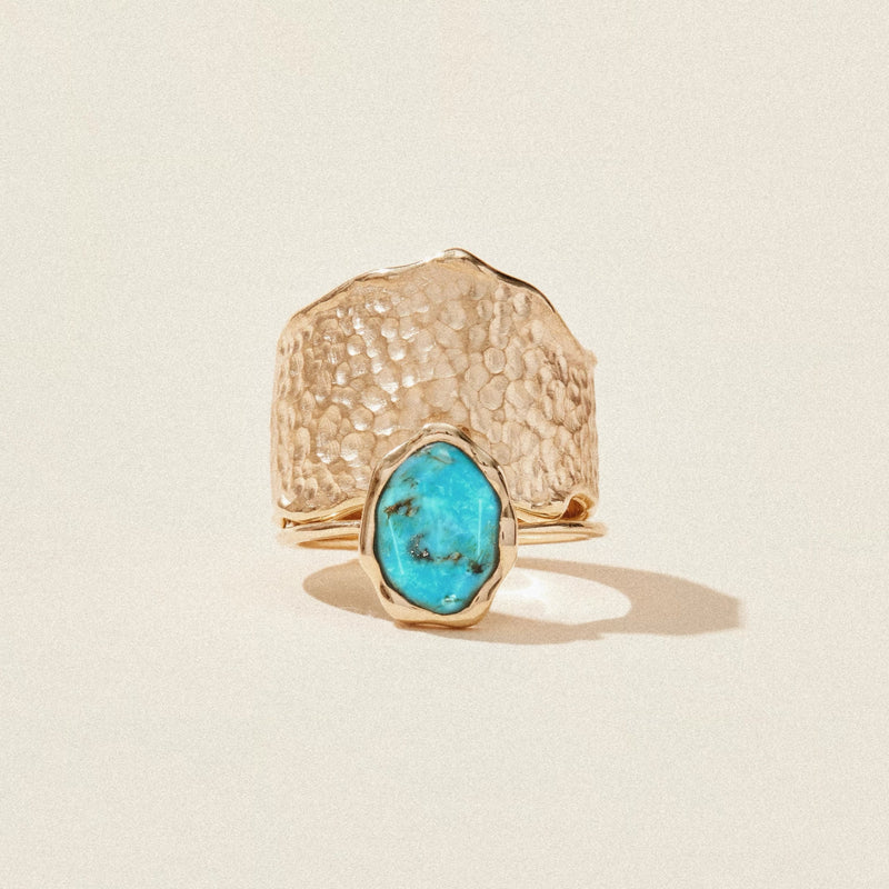 The bluboho turquoise mood ring - 14k yellow gold, turquoise features a wide, hammered band with an irregularly shaped turquoise gemstone at the center. The ring is set against a light, neutral background and casts a soft shadow.