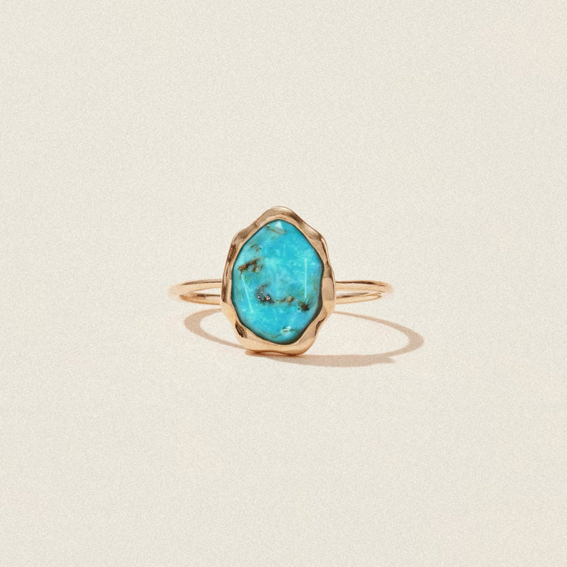 The turquoise mood ring by bluboho showcases a delicate 14k yellow gold band with an asymmetrical turquoise stone set in an organic-shaped bezel. The vibrant, veined turquoise stone contrasts beautifully with the simple, thin gold band, creating a striking yet elegant piece of jewelry.