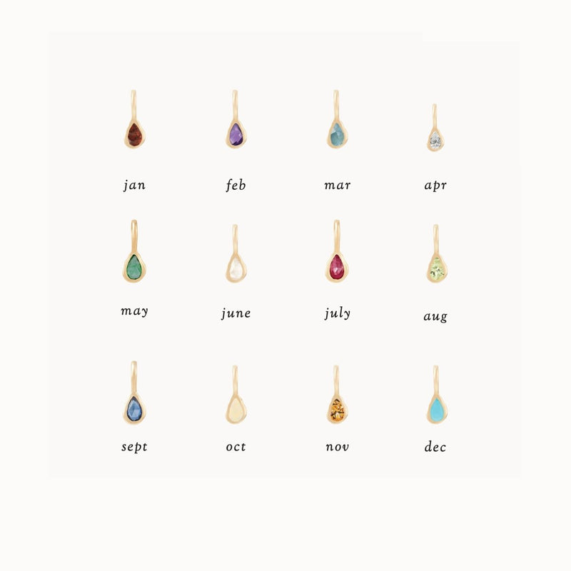 Image displaying a set of twelve small, teardrop-shaped birthstone charms arranged in a 3x4 grid, each representing a different month. The stones are labeled from January to December, with each charm featuring the distinct color of its corresponding birthstone. Highlighted among them is the "pear diamond april mood birthstone charm" crafted in 10k yellow gold with a diamond by bluboho.