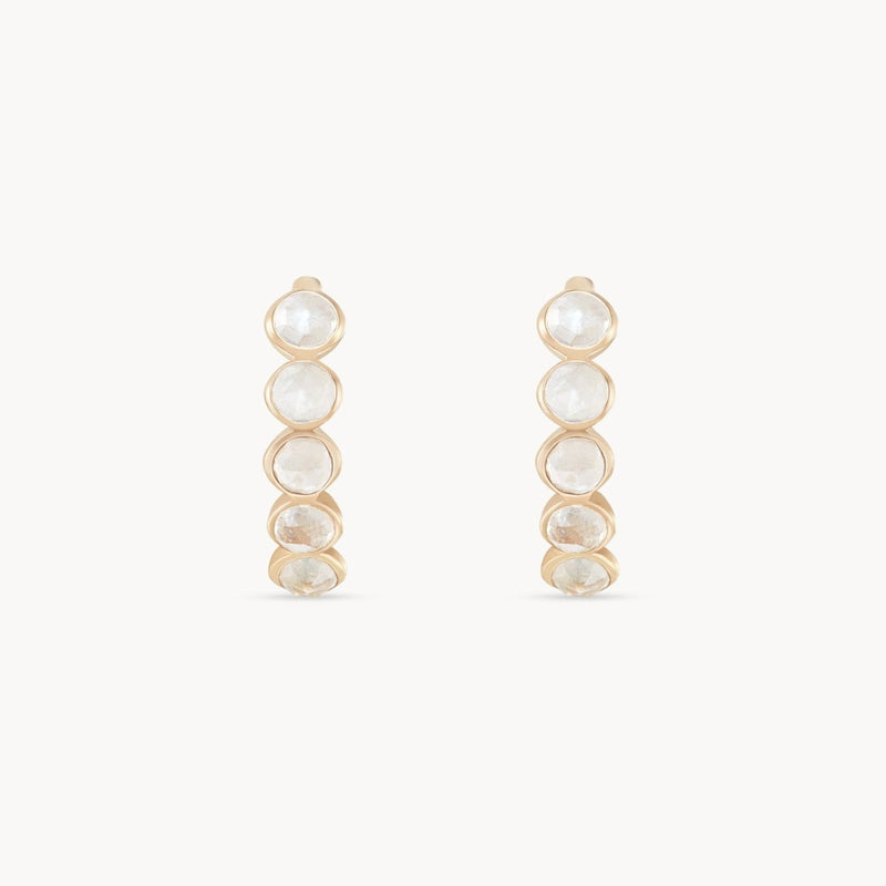 Image shows a pair of bluboho's five stone moonstone mood hoops, featuring a sequence of five graduated, translucent moonstones set in vertical bezel settings. Crafted from 14k yellow gold, these earrings have a minimalist and elegant design. The background is plain white.