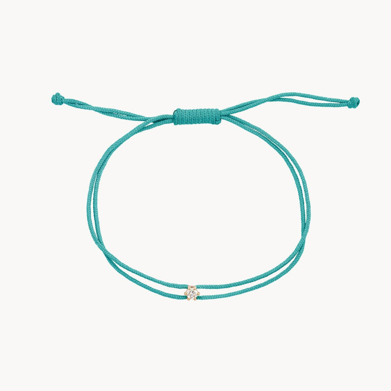 Introducing the nova diamond teal cord bracelet by bluboho. This elegant piece features a yellow gold charm adorned with a delicate diamond at its center, all resting on a teal nylon cord. The adjustable knot closure ensures a comfortable fit, and the minimalist design provides both a casual and sophisticated look.