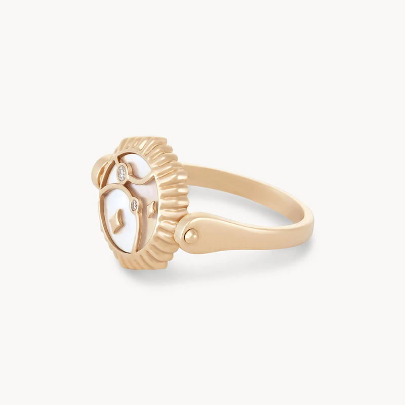 The moon phase flip enamel ring by bluboho is crafted from 14k yellow gold and features exquisite mother of pearl and enamel detailing. Its smooth band complements the intricate design, exuding a blend of elegance and fierceness.