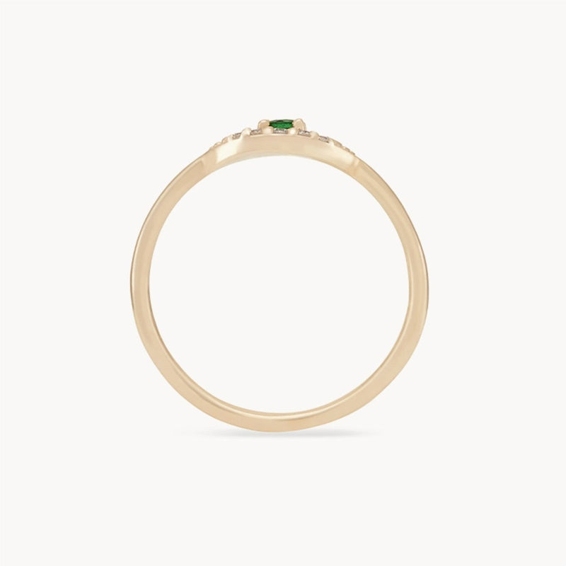 The tsavorite mystical evil eye ring by bluboho showcases a minimalist and elegant design with a thin 14k yellow gold band and a small tsavorite garnet gemstone at the center. It is displayed against a plain white background, emphasizing the single green stone.
