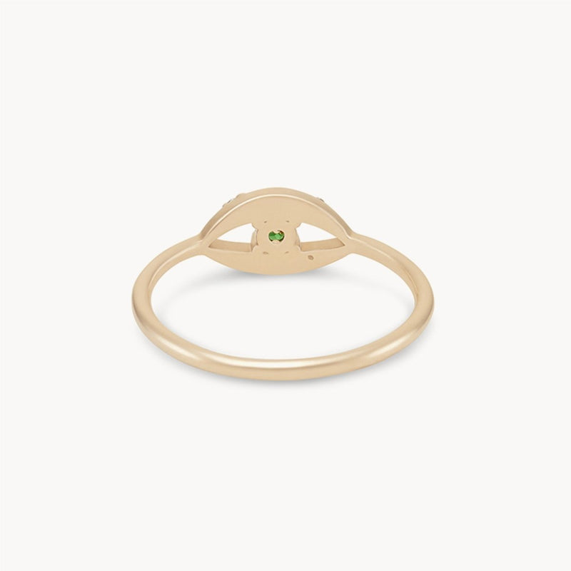 The tsavorite mystical evil eye ring by bluboho, crafted in 14k yellow gold, highlights a central design resembling an eye with a small green tsavorite garnet set at its center. Its band is thin and smooth, epitomizing minimalist elegance against a plain white background that emphasizes the ring's subtle details.
