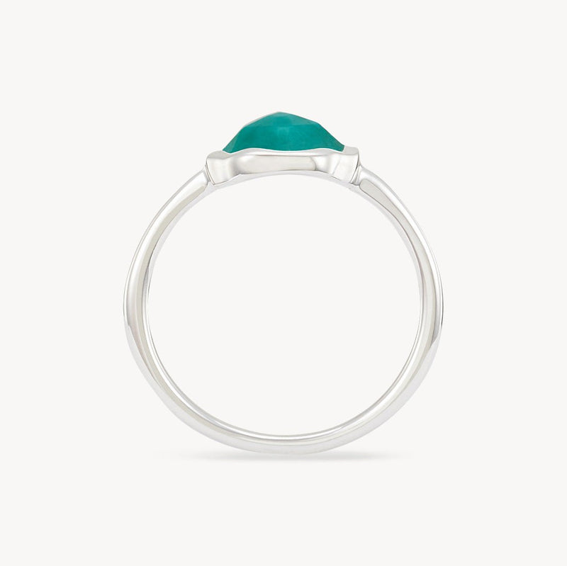 A side view of a bluboho turquoise mood ring silver - sterling silver, turquoise featuring a prominent, faceted teal gemstone. The ring has a simple, sleek band with the gemstone set in a low-profile prong setting. The background is plain white, highlighting the elegant and minimalistic design of the ring.