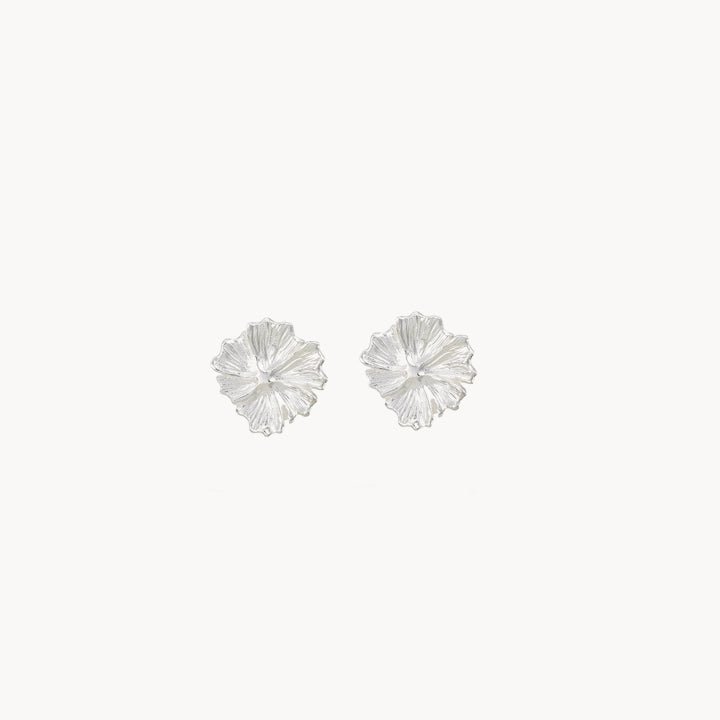 A pair of larger wildflower earrings in sterling silver, designed by bluboho to resemble flower petals. Intricate detailing radiates from the center, with a plain white background accentuating the earrings' shine and delicate craftsmanship.